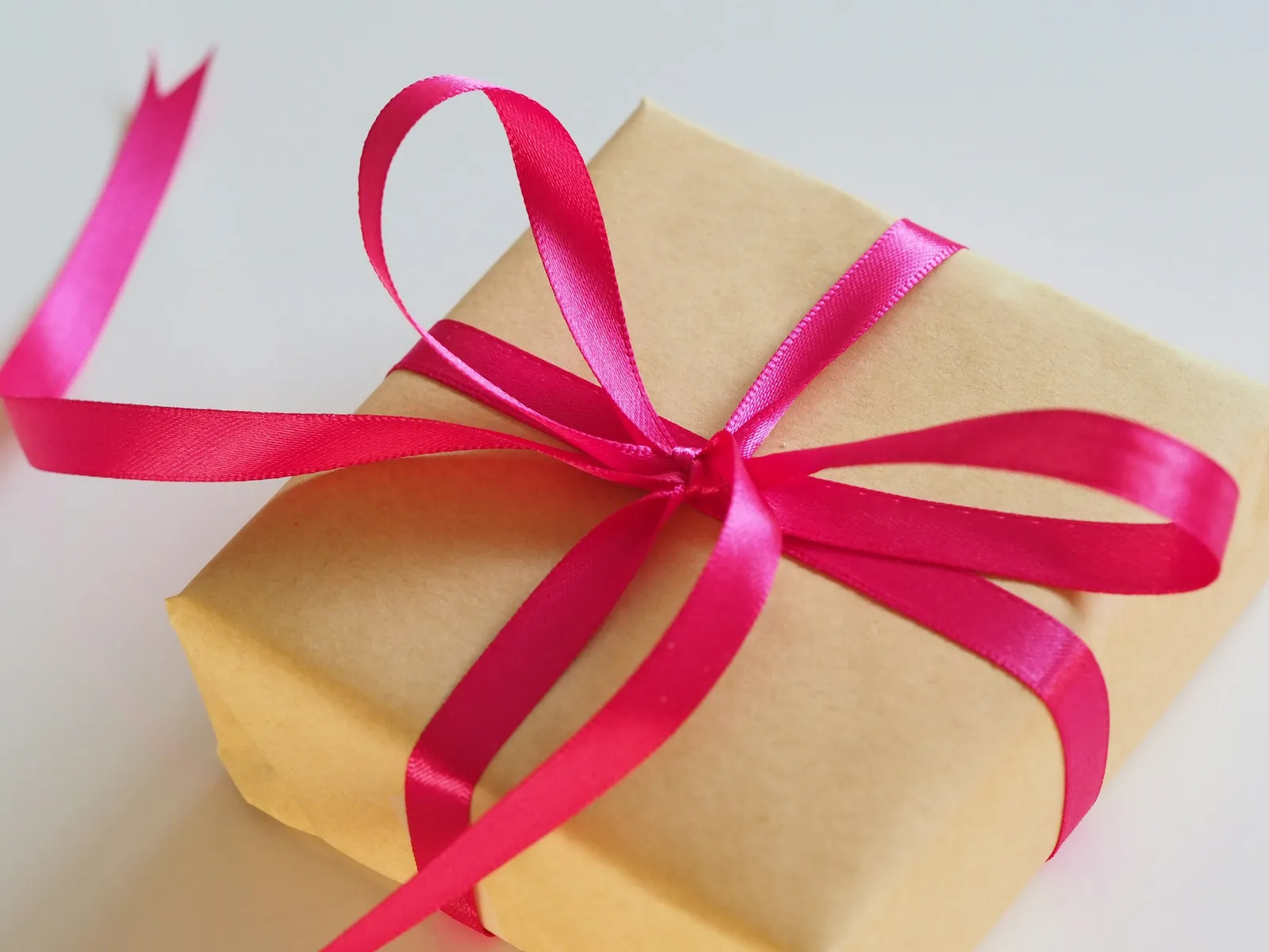 Paquet cadeau en papier kraft noué d'un ruban de satin rose