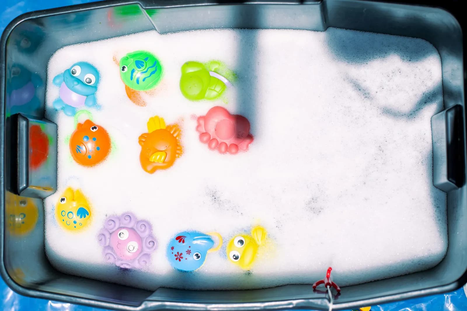 Jouets de bain en forme d'animaux marins dans un bac rempli de mousse, vus du dessus