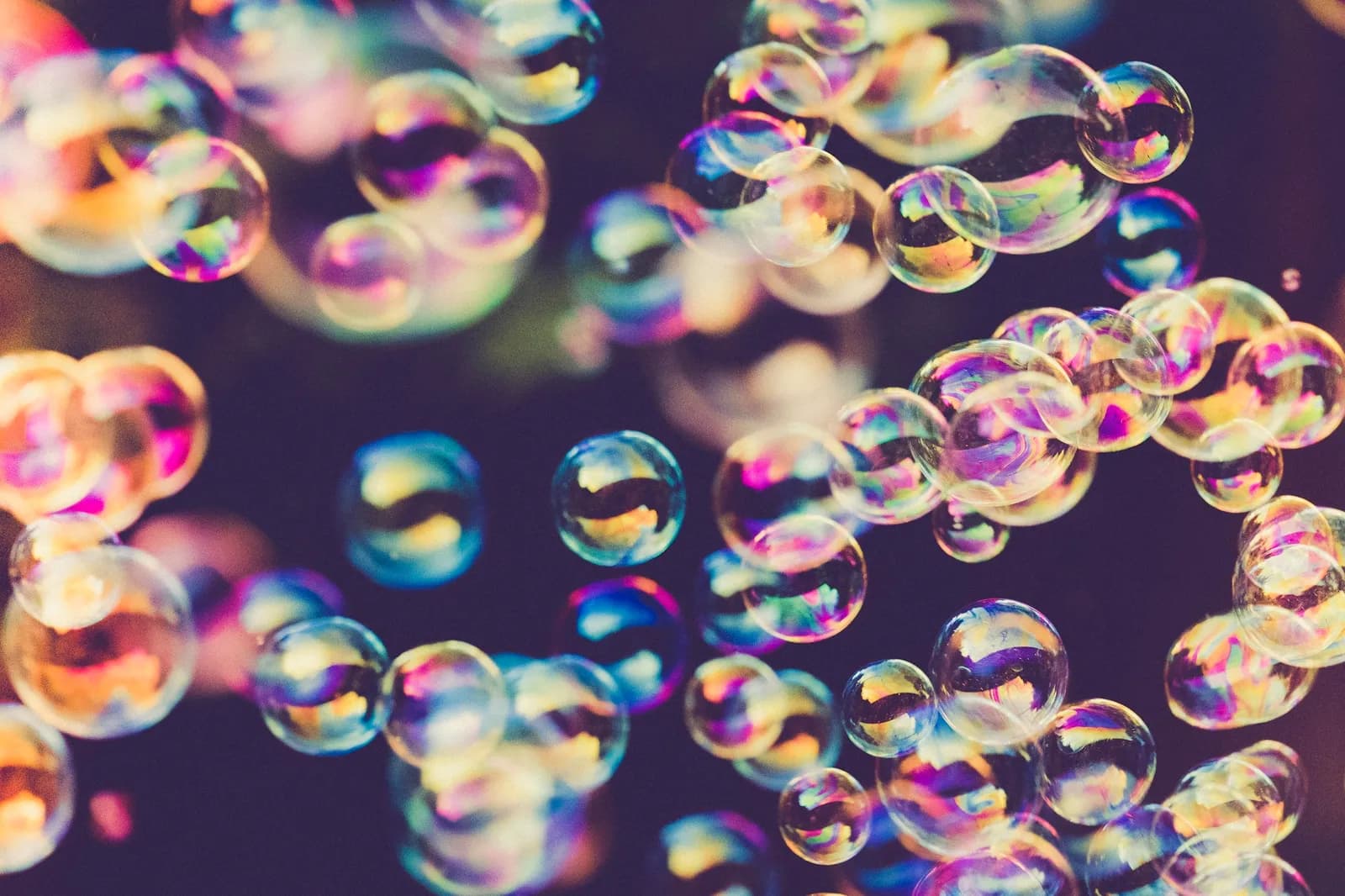 Nuée de bulles de savon irisées sur un fond sombre