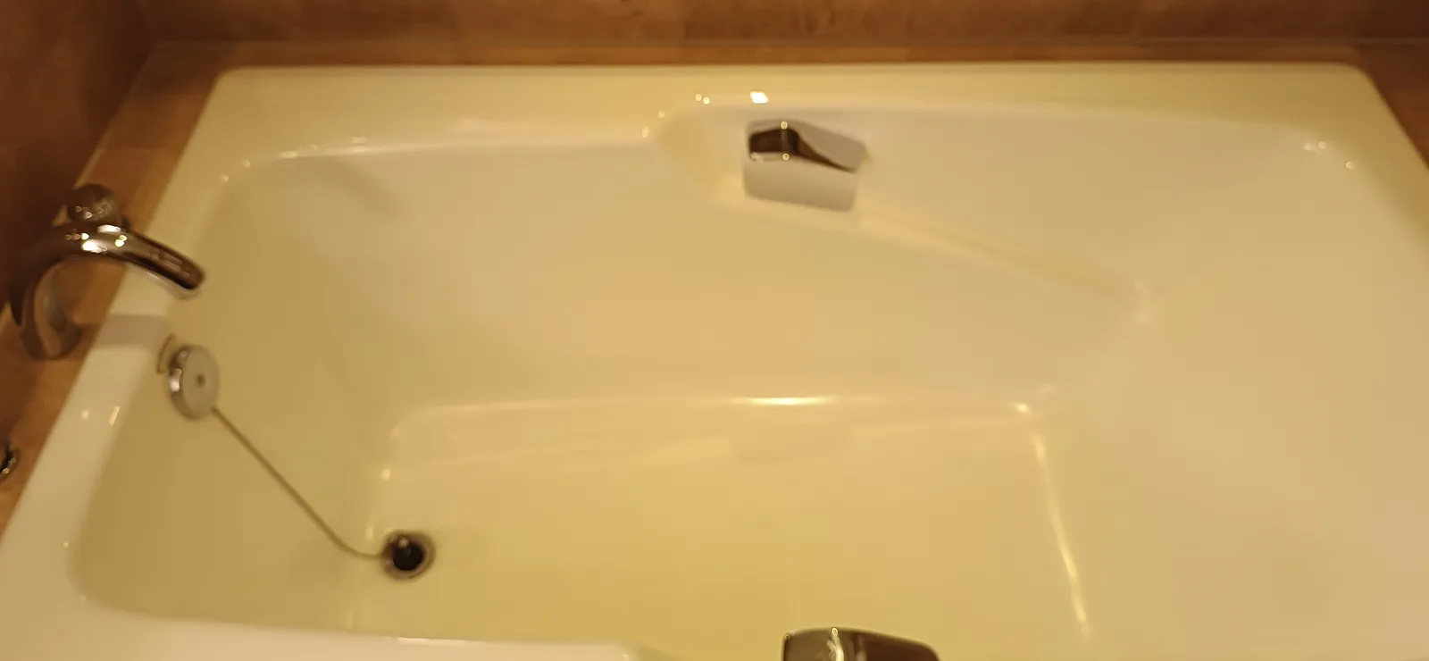 Baignoire blanche vide, bonde ouverte, avec son robinet en métal chromé