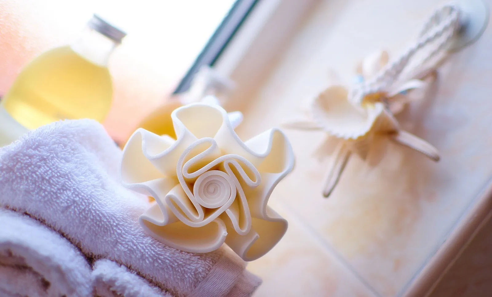 Serviettes blanches pliées, à côté d'une fleur de douche et d'un flacon